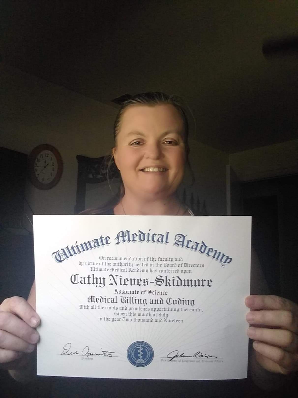 Cathy holding up her degree from Ultimate Medical Academy in 2019.